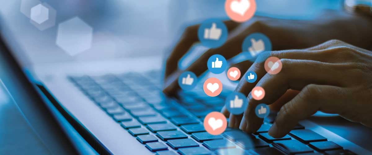 digital-marketing-trends-social close up of hands using laptop. Social media "like" icons floating in foreground